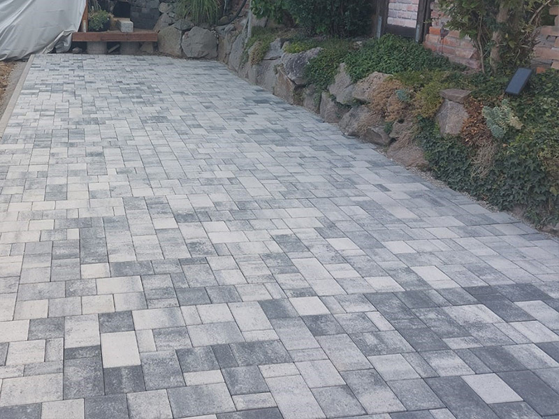 : Außenanlage mit Unterbau, Pflaster und Granit Stele gestaltet