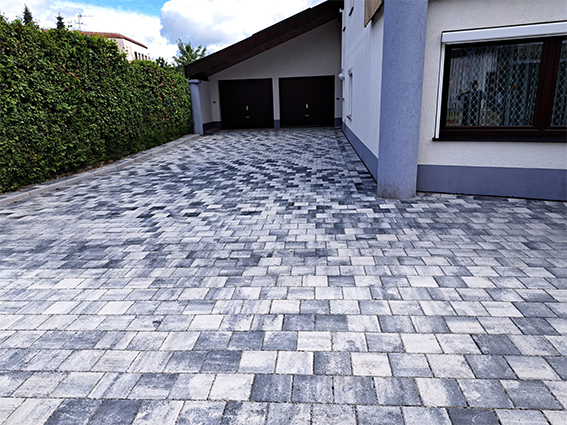 Verlegung von Pflaster und Schachtabdeckung mit Natursteinen integriert.